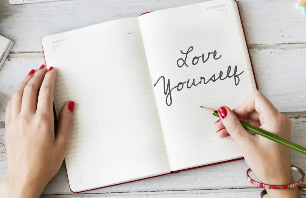 Woman writing in journal things I love about myself