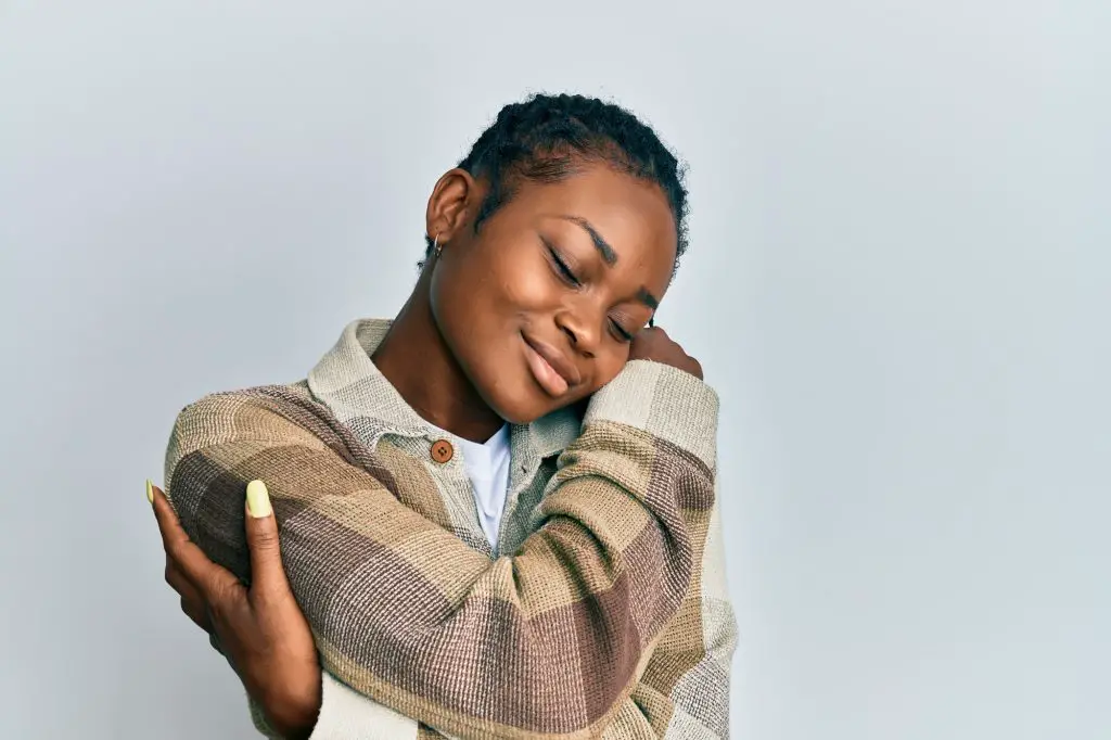 Young African American woman wearing casual clothes hugging oneself happy and positive, smiling confident. self-love and self-care