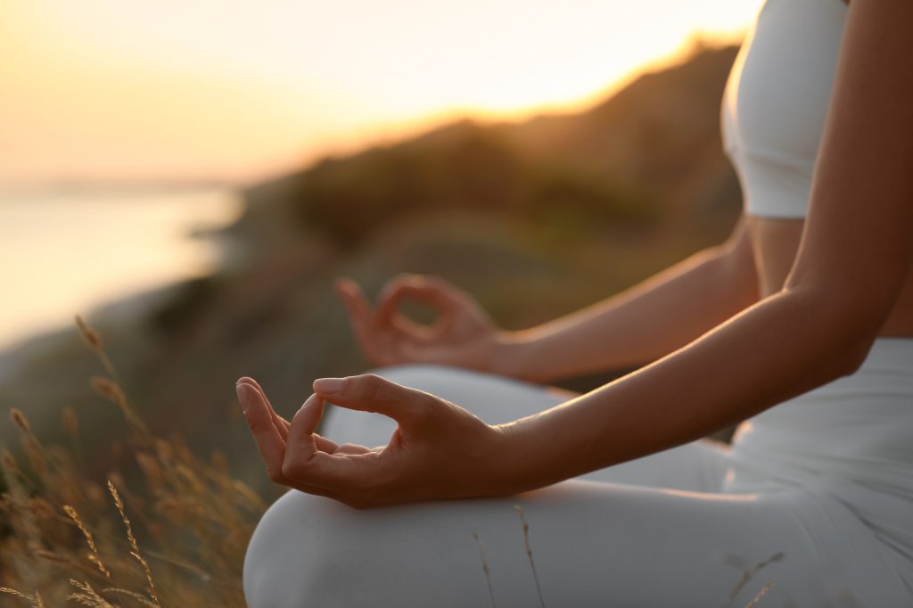 Woman meditating outdoors at sunset, closeup view