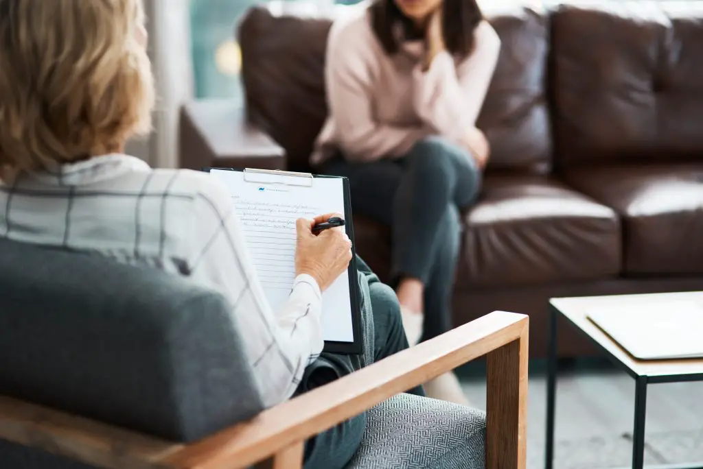 Keep talking until the answers become clearer. a psychologist writing notes during a therapeutic session with her patient