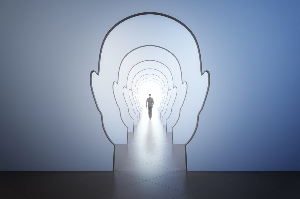 Success psychology and business motivation concept with walking man back leading to light spot in the end of corridor through walls in form of human heads