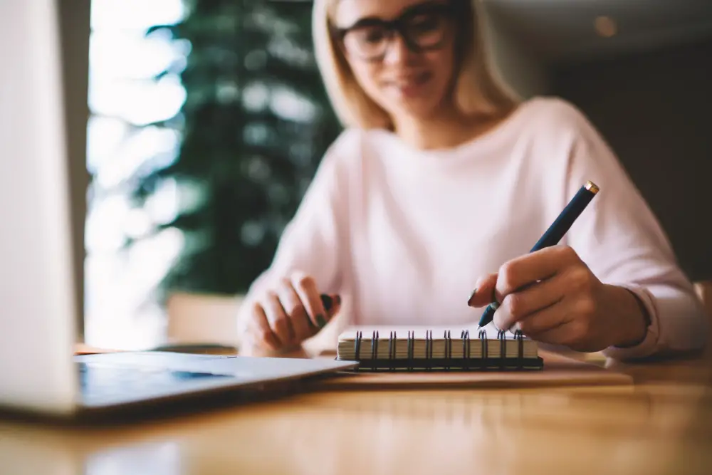 a woman writing on a notebook