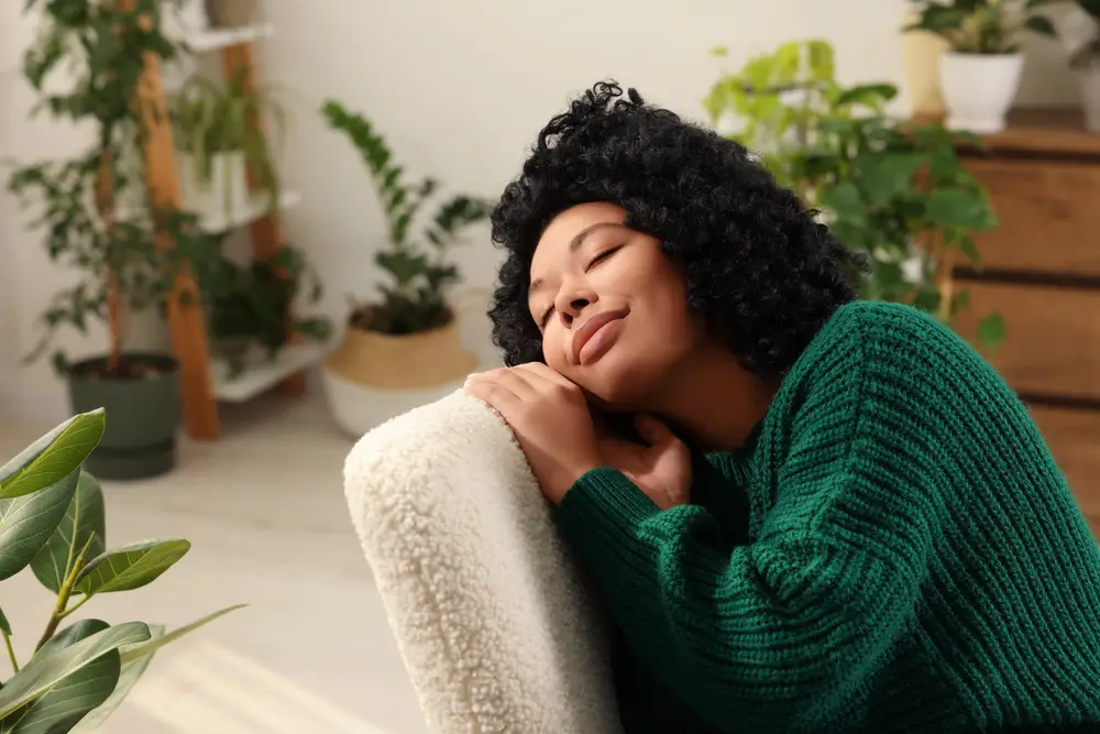 Woman relaxing surrounded by beautiful houseplants at home. Space for text