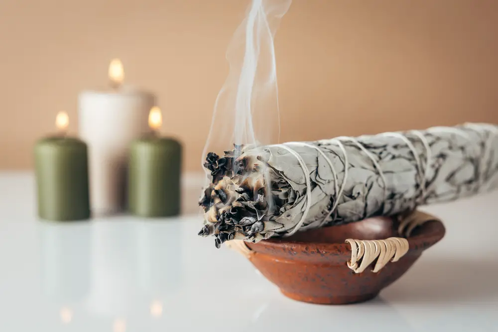 White sage and burning candles in background 