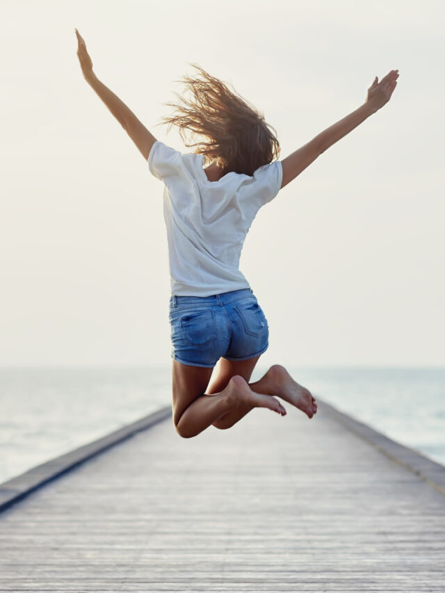 Back view of jumping girl on the pier